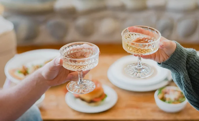 Couple enjoying food and drinks in front of a stone fireplace