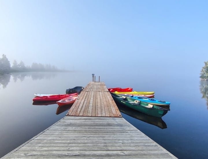 a dock on a lake with moored kayaks