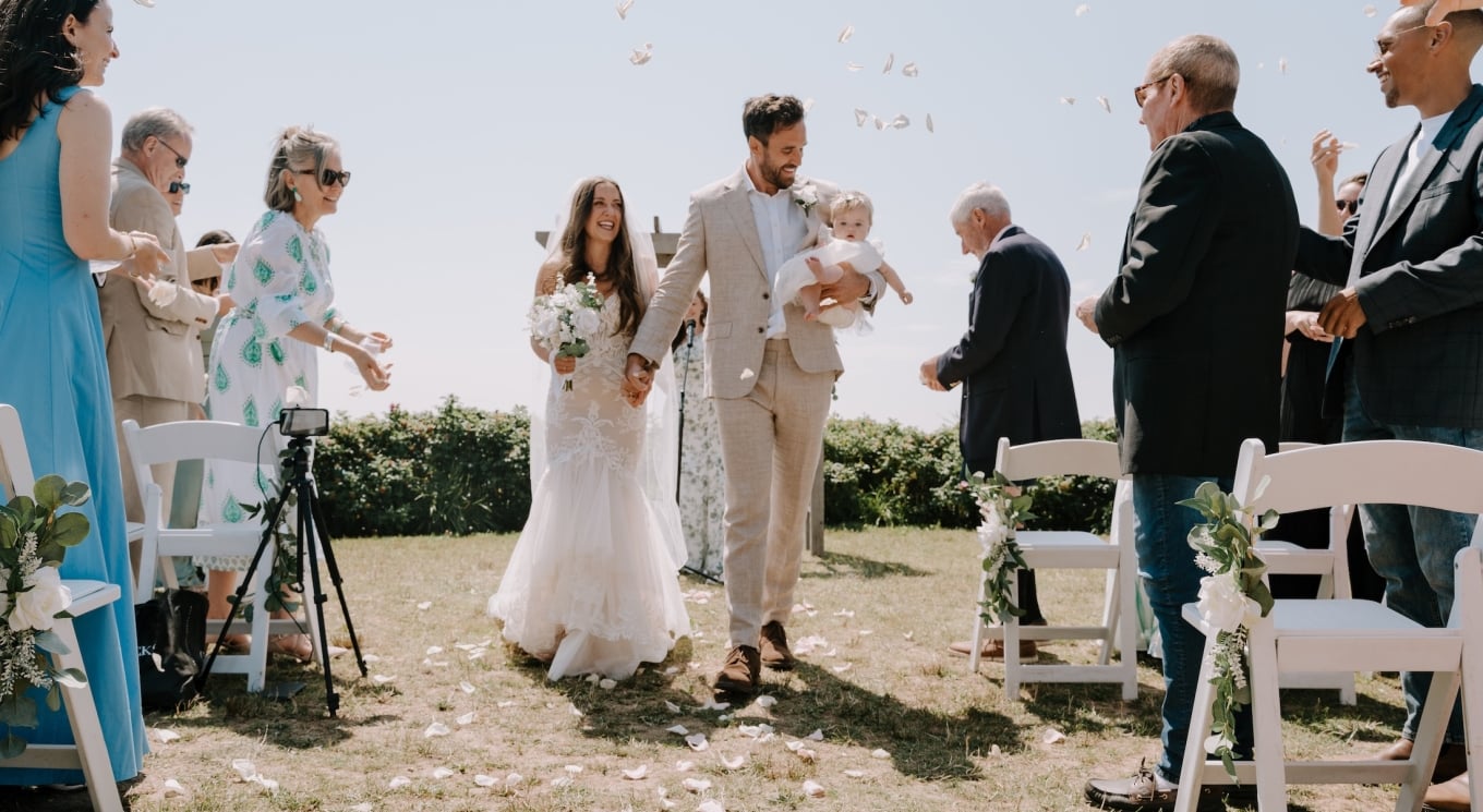 a bride and groom walking down a wedding aisle with a baby