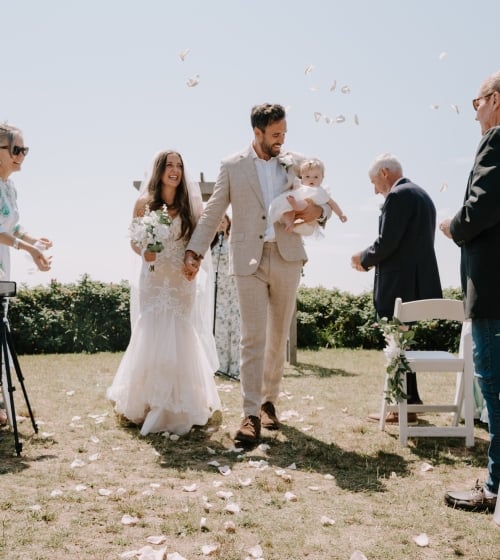 a bride and groom walking down a wedding aisle with a baby
