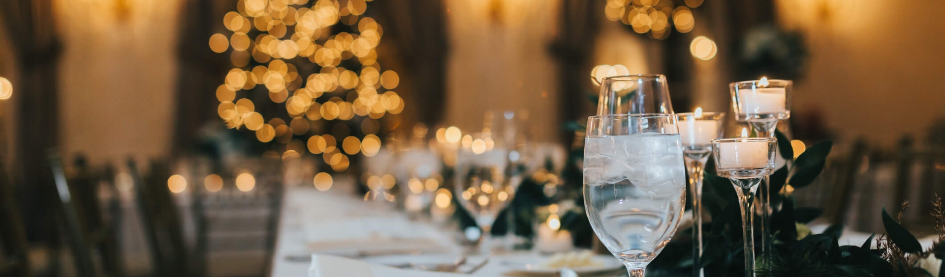 A long table with a white table cloth set for a dining event